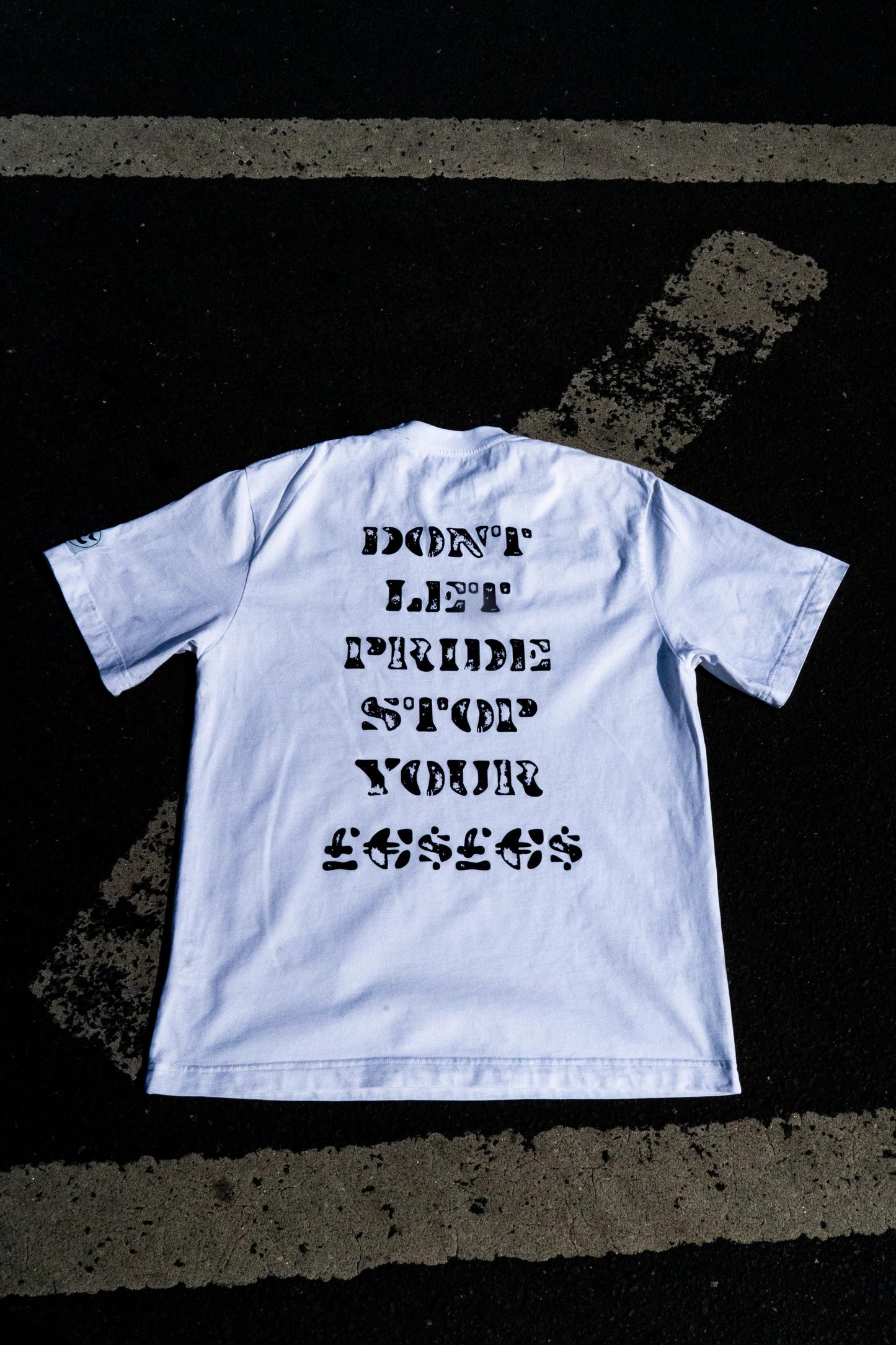 White t-shirt with black text on a dark textured surface
