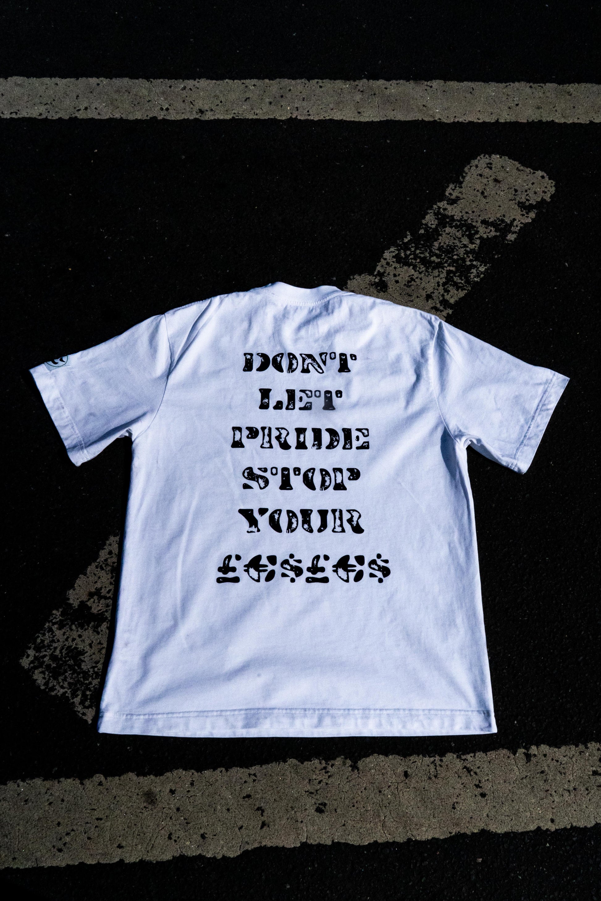 White t-shirt with black text on a dark textured surface